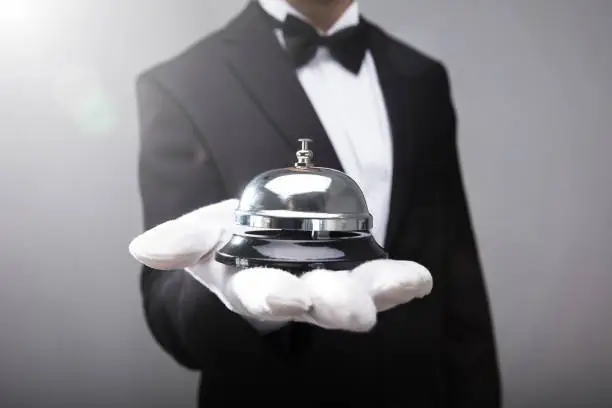 Close-up Of A Waiter's Hand Holding Service Bell