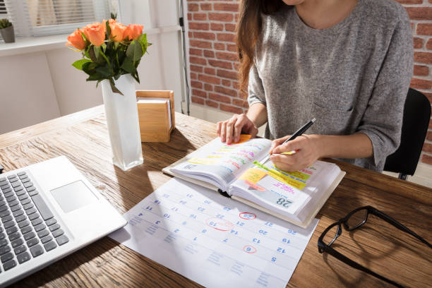 Businesswoman Making Schedule On Personal Organizer Close-up Of A Businesswoman Making Agenda On Personal Organizer At Workplace personal organiser stock pictures, royalty-free photos & images