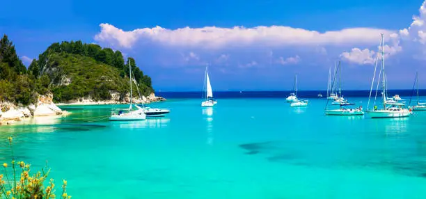 Photo of Beautiful turquoise bay Lakka in Paxos with sailing boats. Ionian islands of Greece