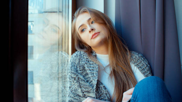 istock Young pensive woman sitting by a window. 924569092