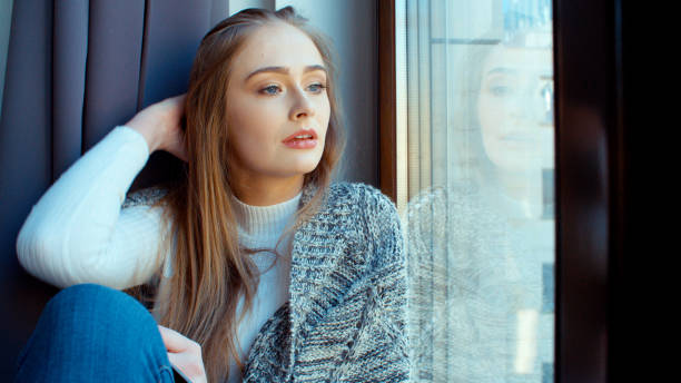 istock Young pensive woman sitting by a window. 924569130