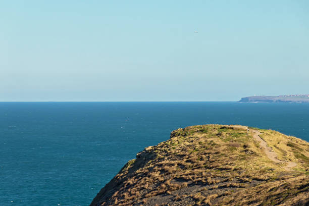 istock Grass covered cape over beautiful blue sea landscape under sunlight 924572286