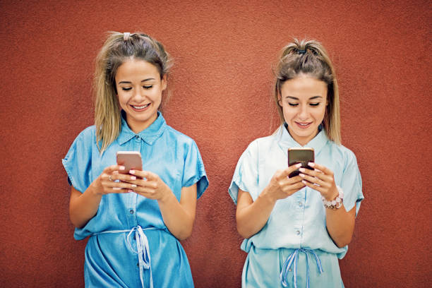 istock Happy twin sisters are texting 924579682