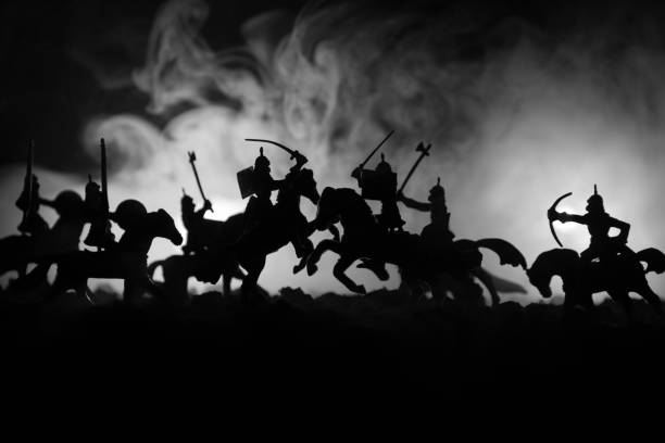 istock Medieval battle scene with cavalry and infantry. Silhouettes of figures as separate objects, fight between warriors on dark toned foggy background. Night scene. 924589582