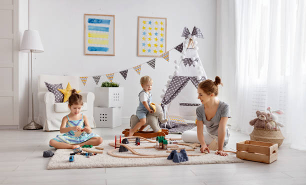 familie mutter und kinder spielen eine spielzeug-eisenbahn im spielzimmer - child playroom parent indoors stock-fotos und bilder