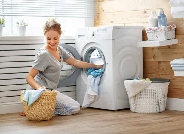 happy housewife woman in laundry room with washing machine - contemporary indoors lifestyles domestic room imagens e fotografias de stock