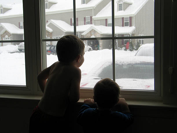 istock Children Looking out Window During Snow Storm on Winter Day 92462031