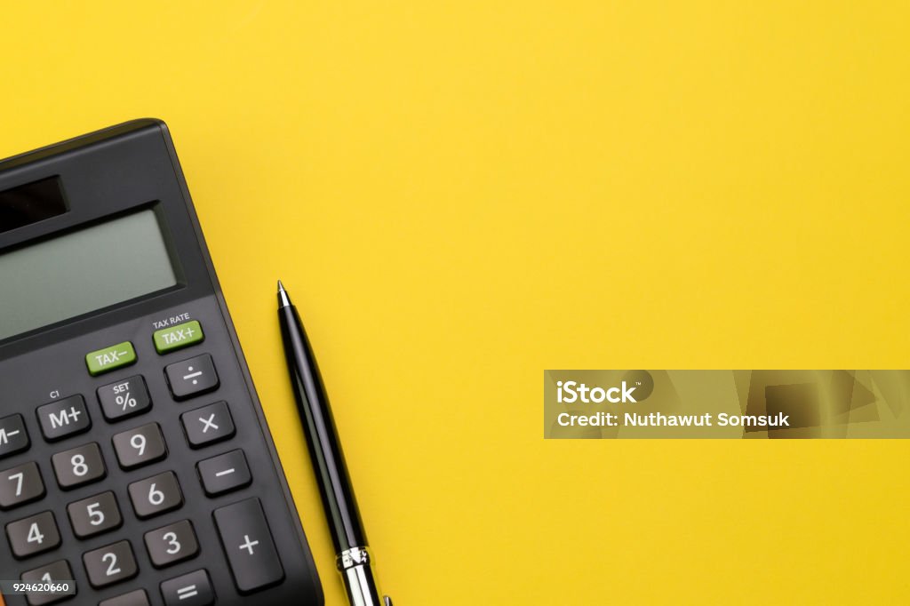 Flat lay or top view of black pen with calculator on vivid yellow background table with blank copy space, math, cost, tax or investment calculation Flat lay or top view of black pen with calculator on vivid yellow background table with blank copy space, math, cost, tax or investment calculation. Calculator Stock Photo