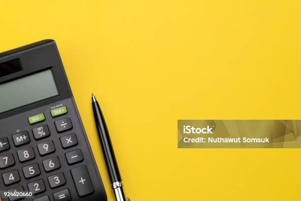 Flat Lay Or Top View Of Black Pen With Calculator On Vivid Yellow Background Table With Blank Copy Space Math Cost Tax Or Investment Calculation Stock Photo - Download Image Now