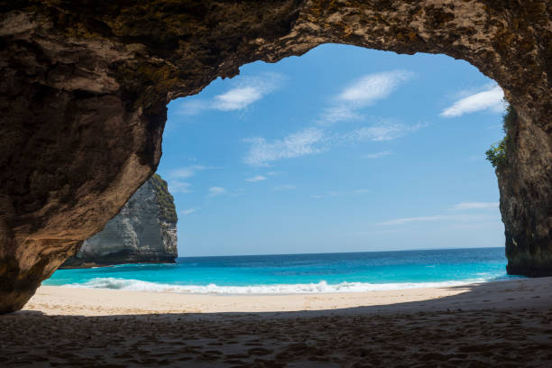 Cave and tropical sea at Kelingking Beach, Nusa Penida View of the beach and sea from a cave at Kelingking Beach on the tropical Indonesian island of Nusa Penida. kelingking beach stock pictures, royalty-free photos & images