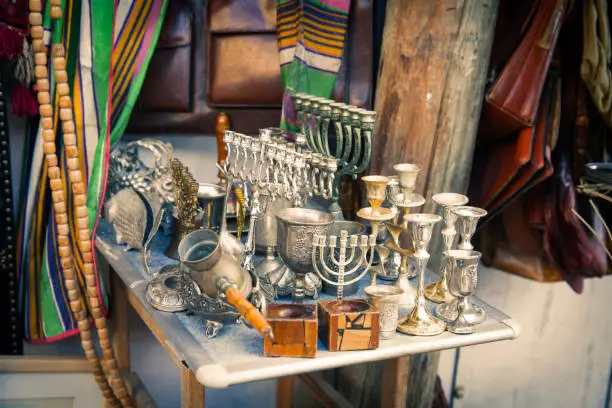 Table with menorah and Kiddush wine cups,and other items at  the flea market. - Tel Aviv, Israel