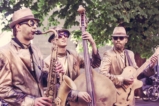 Konstanz, Germany - August 3, 2012. A jazz band performs live music on the street, wearing suits, hats and sunglasses; with everything painted in copper/brass colours, including clothes, skin and instruments.