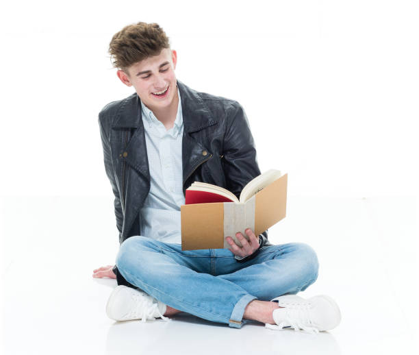 istock Attractive young man holding books and sitting on floor 924635340