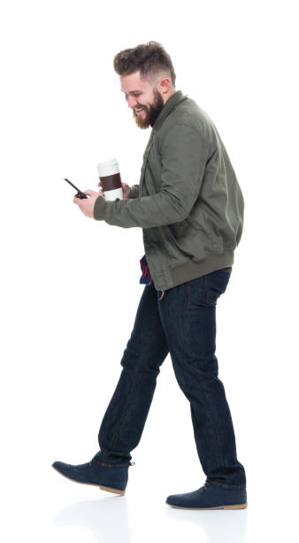 istock Cool guy with jacket and red shirt holding coffee and using smart phone 924635388