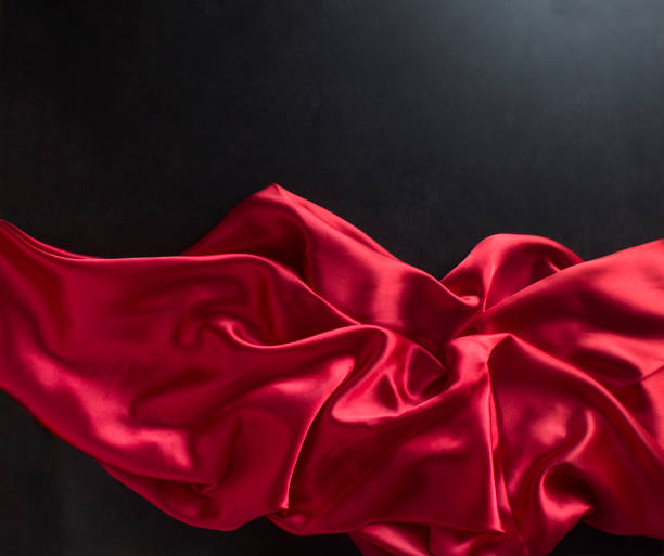 istock Red satin fabric flowing on black background. 924635522
