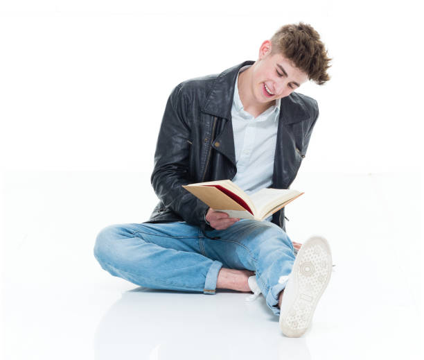 istock Attractive young man holding books and sitting on floor 924640972