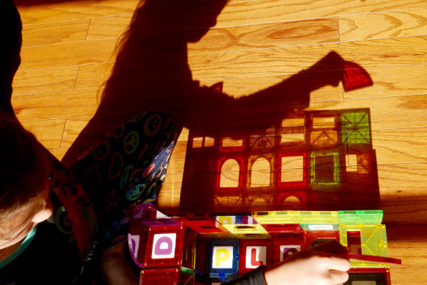 Colorful shadow of girl playing with magnetic building tiles