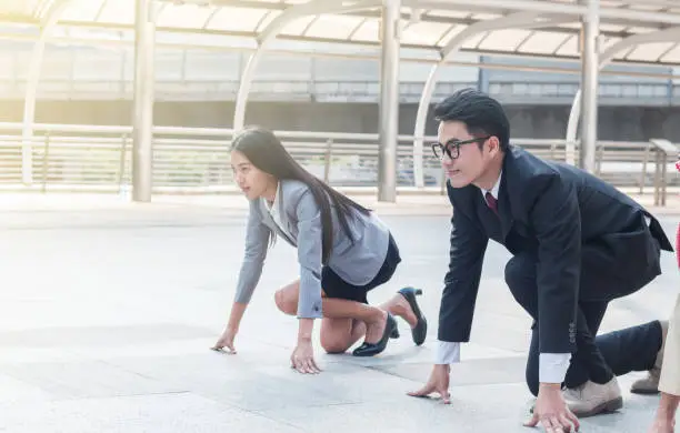 The businessman and businesswoman ready to run on start position with challenge and commitment to success (This photo taken at skywalk Chong Nonsi BTS Station which is public)