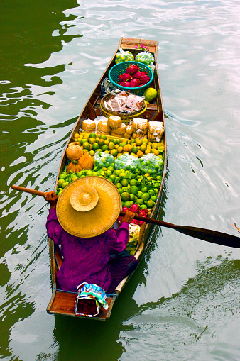 Selective focus on hat of vendor on boat in traditional floating market Damnoen Saduak near Bangkok, Thailand