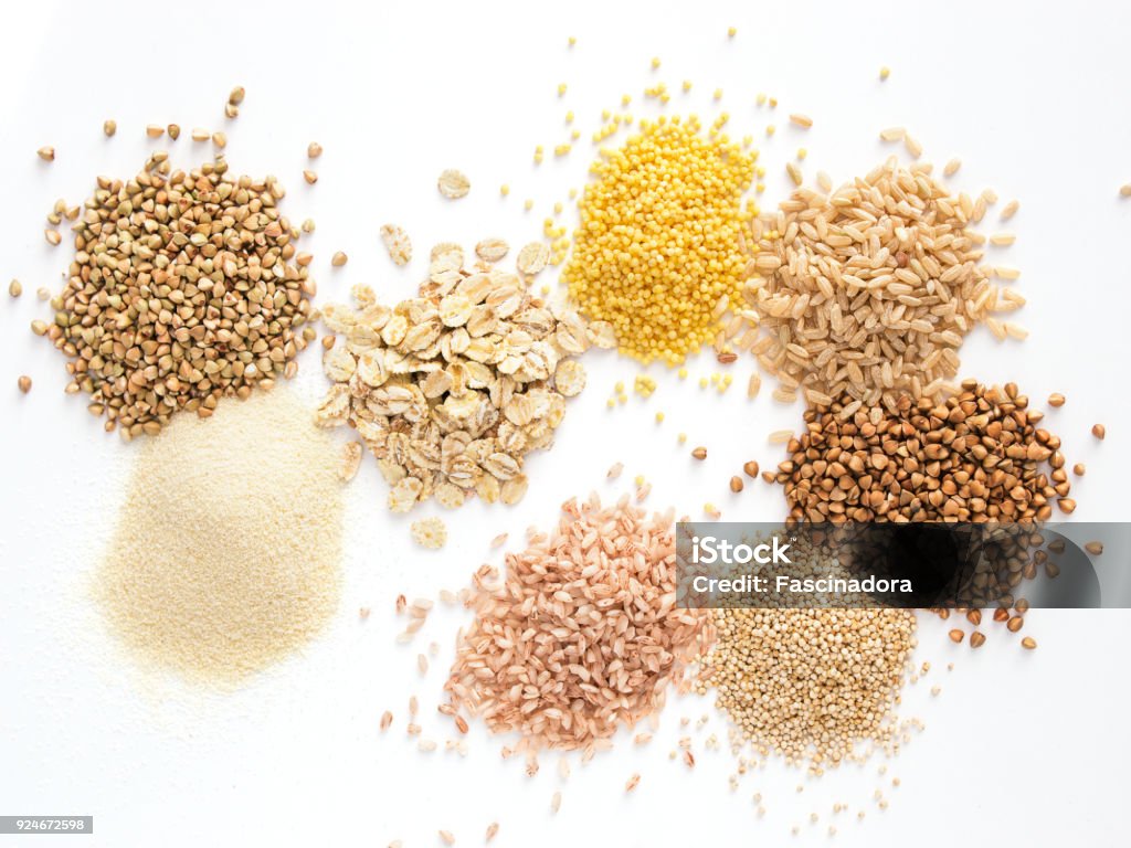 Set of heap various grains and cereals isolated Set of heap various grains and cereals - raw green buckwheat, semolina, oat flakes, millet, brown rice, buckwheat or kasha,quinoa, and red rice.Isolated on white with clipping path.Top view.Copy space Cereal Plant Stock Photo
