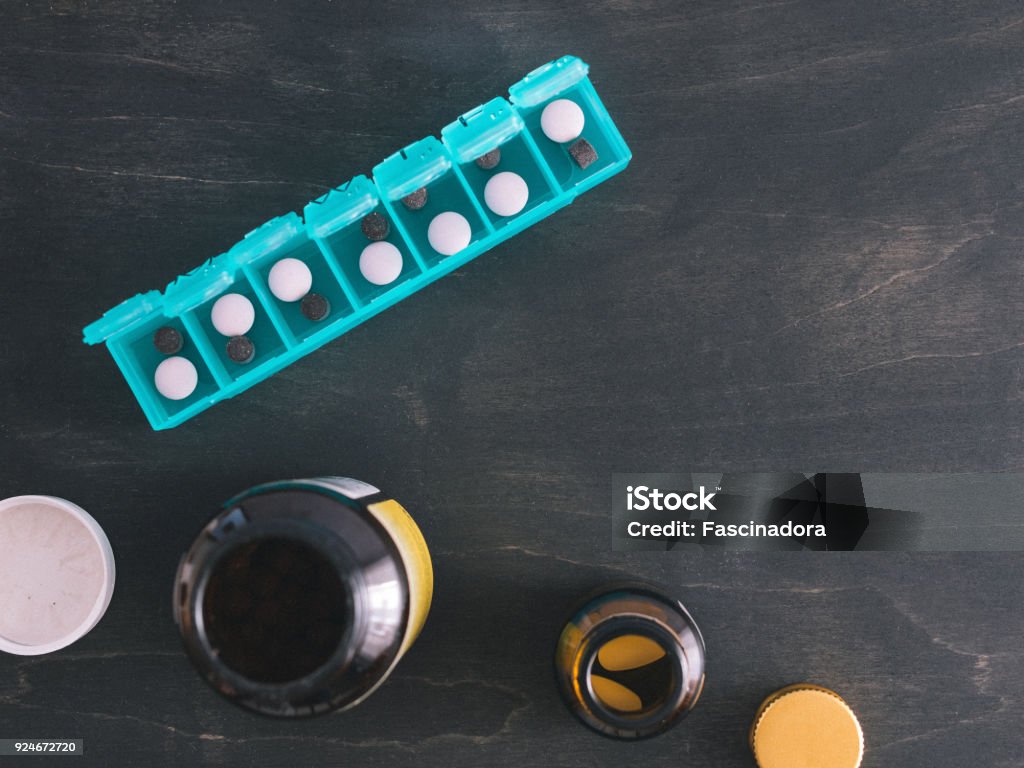 top view of pill box with copy space Top view of seven day pill box with pills. Green pill-box over dark wooden table. Open pill box and open boxes with pills or vitamins. Copy space. Top view or flat-lay. Pill Stock Photo