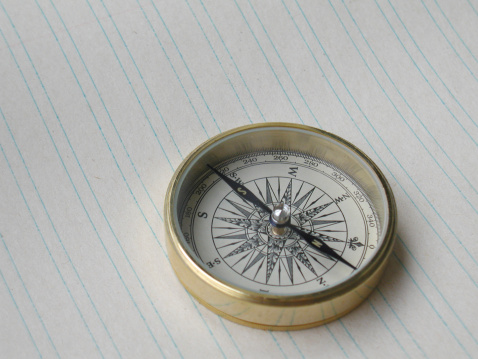 A compass on an old and lined sheet of paper.