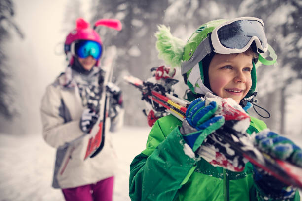 niños llevando agua en un día de invierno hermosa - skiing snow skiing helmet fun fotografías e imágenes de stock