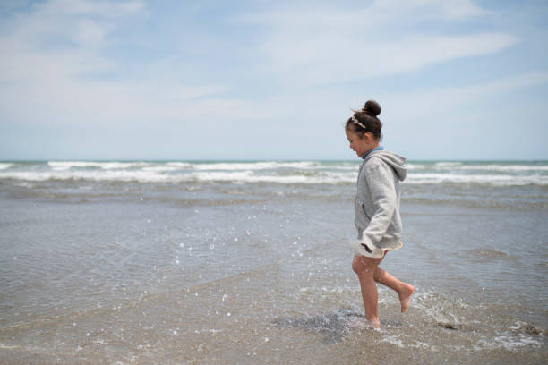 istock Little girl playing in the spring sea 924680992