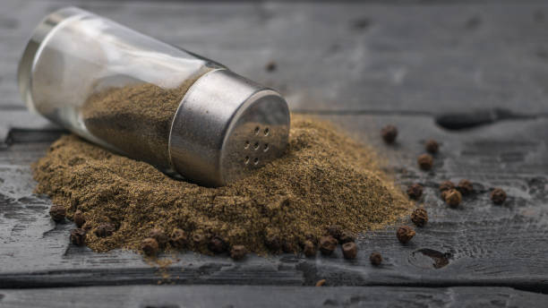 istock Ground pepper is poured from a glass jar on a wooden table. 924684374