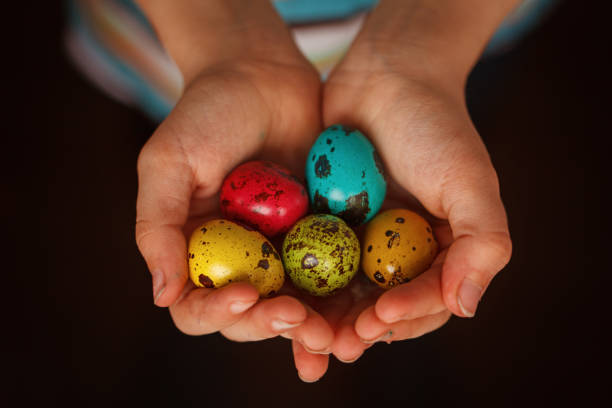 istock Child's hands holding colored quail eggs on pink background. Easter Spring holiday concept 924688586
