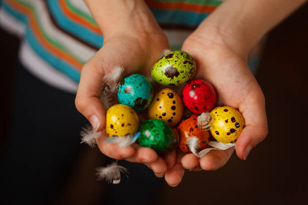 istock Child's hands holding colored quail eggs on pink background. Easter Spring holiday concept 924688686