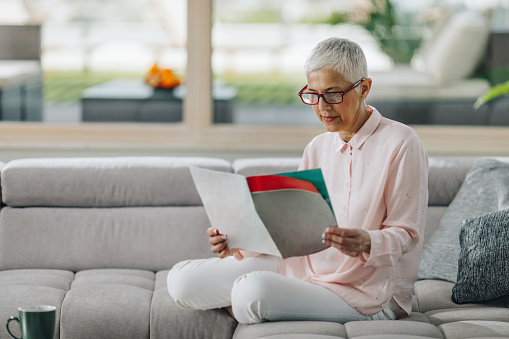 Mature woman reading a magazine and enjoying in her time at home.