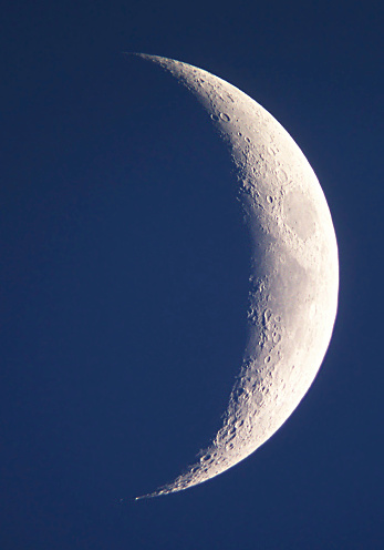 Waxing gibbous moon in a clear blue evening sky - Detailed close up with craters