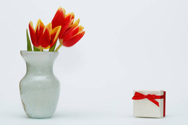 istock March 8! Vase with tulips and a gift with a red bow on a white background. 924713984