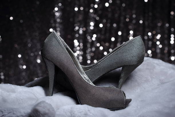 Black pump shoes besides the bed. Selective focus on left most shoe.Related:
