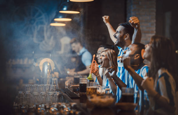 istock Happy soccer fans cheering while watching a game in a bar. 924723948