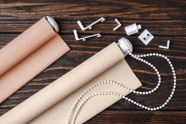 The beige rolled blind is on a wooden surface.
