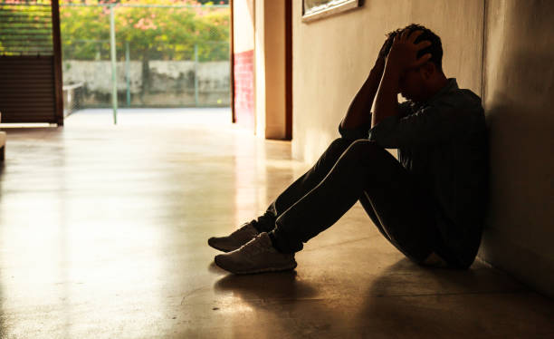 moment d’émotion : homme assis tenant la tête dans les mains, a souligné triste jeune mâle ayant des problèmes de santé mentale, se sentant mauvais, déprimés, déçus, sans espoir. homme désespéré dans le coin sombre, ayant besoin d’aide. - maladie mentale photos et images de collection