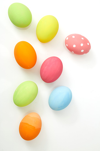 An Easter egg decorated and painted by male hands is photographed over a light gray table with natural light