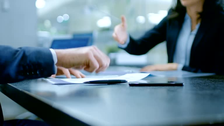 In the Office Close-up on Hands of Businesswoman and Businessman while Signing Contracts and Shaking Hands for Finishing Transaction. Stylish People in Modern Conference Room.