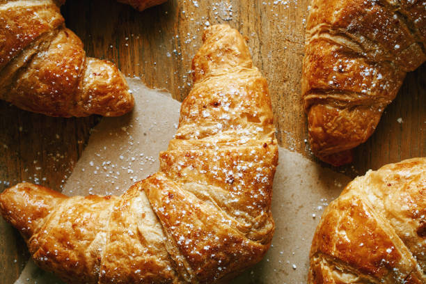 Closeup of freshly baked croissants on wooden table.