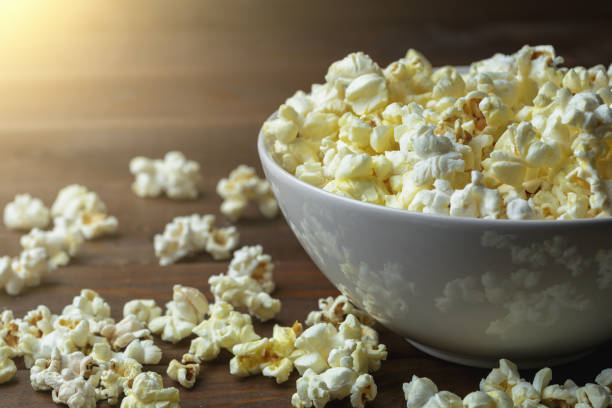 istock Popcorn in white bowl on wooden table in sunlight effect 924741422