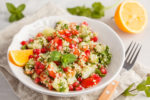Tabbouleh salad with tomato, cucumber, couscous, mint and pomegranate. Vegan Healthy Food Concept. Traditional middle eastern or arab dish.