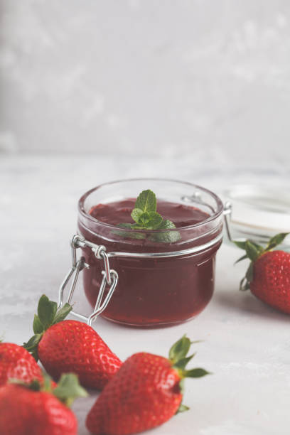istock Strawberry jam in a glass jar with berries, gray background. 924745144