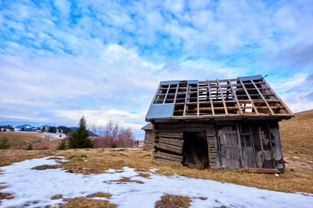 old and broken wooden house in the middle of the hill in winter day.