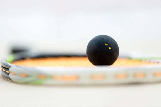 Black squash ball on rackat close up shot stock photo