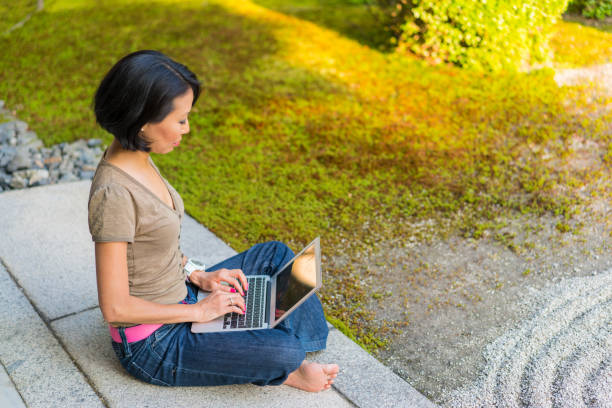 widok z boku kobieta siedzi na podium świątyni, wpisując na laptopie podczas korzystania z ogrodu zen świątyni chion-ji w kioto, japonia - zen like women temple meditating zdjęcia i obrazy z banku zdjęć