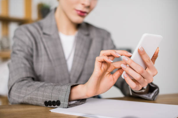 istock cropped shot of businesswoman using smartphone while sitting at workplace in office 924769880