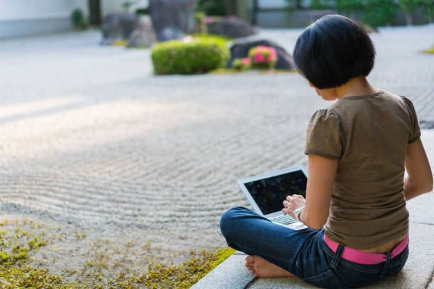 side, widok z tyłu kobieta siedzi na podium świątyni, wpisując na laptopie podczas korzystania z ogrodu zen świątyni chion-ji w kioto, japonia - zen like women temple meditating zdjęcia i obrazy z banku zdjęć