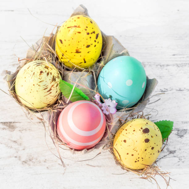 istock Easter eggs in egg cartoon box on white rustic wooden background close up. Festive decorations. Happy Easter!